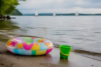 Detské hračky na piesku pri plytkom jazere.