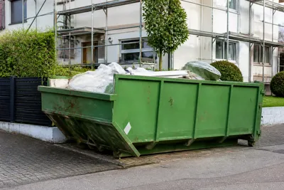 Preplnený zelený kontajner pred domom, príklad nesprávne naloženého odpadu