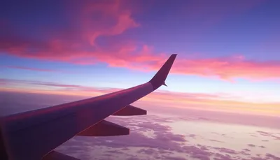 Krídlo lietadla pri západe slnka z pohľadu cez okienko