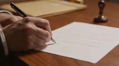 Ruka podpisuje dokument perom na stole