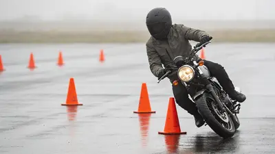 Motorkár v prilbe a rukaviciach precvičuje jazdu medzi kužeľmi na cvičisku