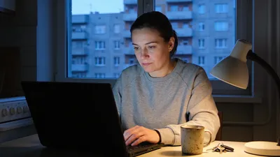 Žena si večer v panelákovom byte upravuje životopis na notebooku